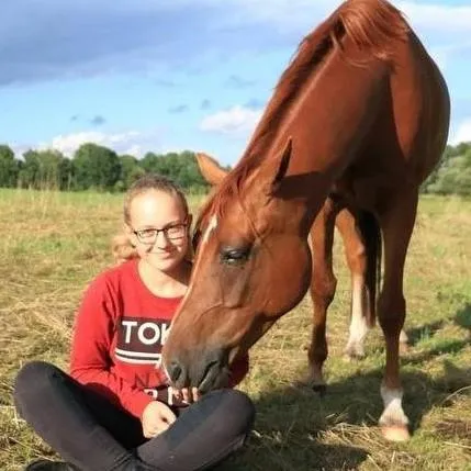 Girl sitting on the ground with a horse