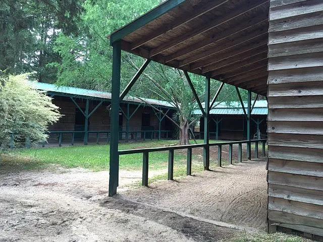 Barn at Pony Gang Equestrian Services, home of Spotted Gang Appaloosas, showing covered walkway and green-trimmed stalls.