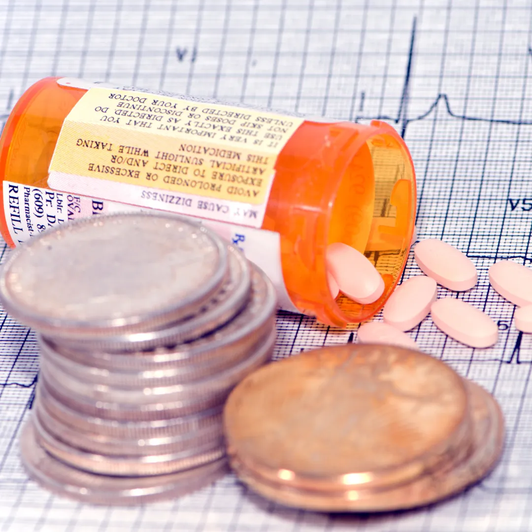 Prescription bottle with coins in front of it.