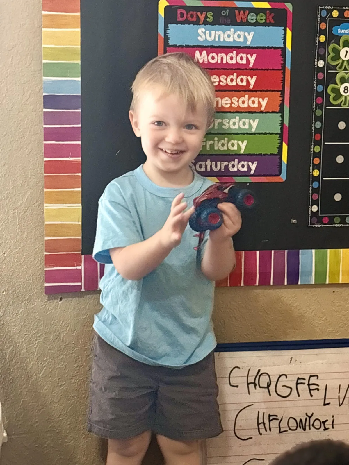 Child writes A in green sand