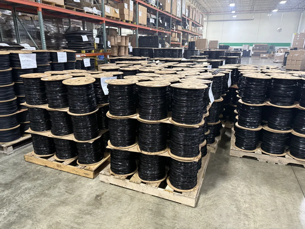 Reels of black extruded rubber product stacked on wooden skids in the Orazen Extruded Polymers warehouse