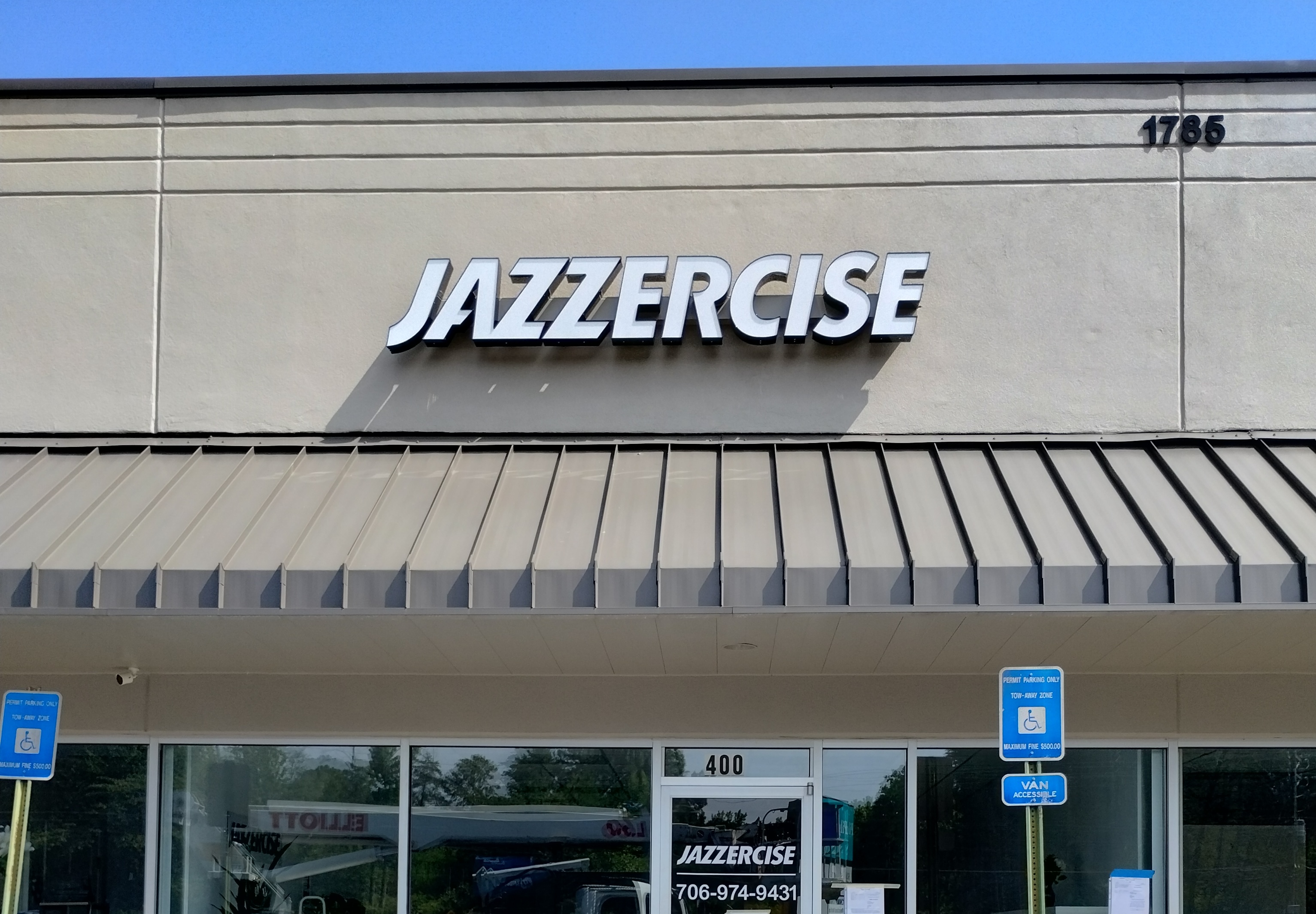 Custom front-lit channel letters for Homestead, featuring individual 3D black lettering mounted on a modern wood-slat storefront facade for high-impact retail branding.
