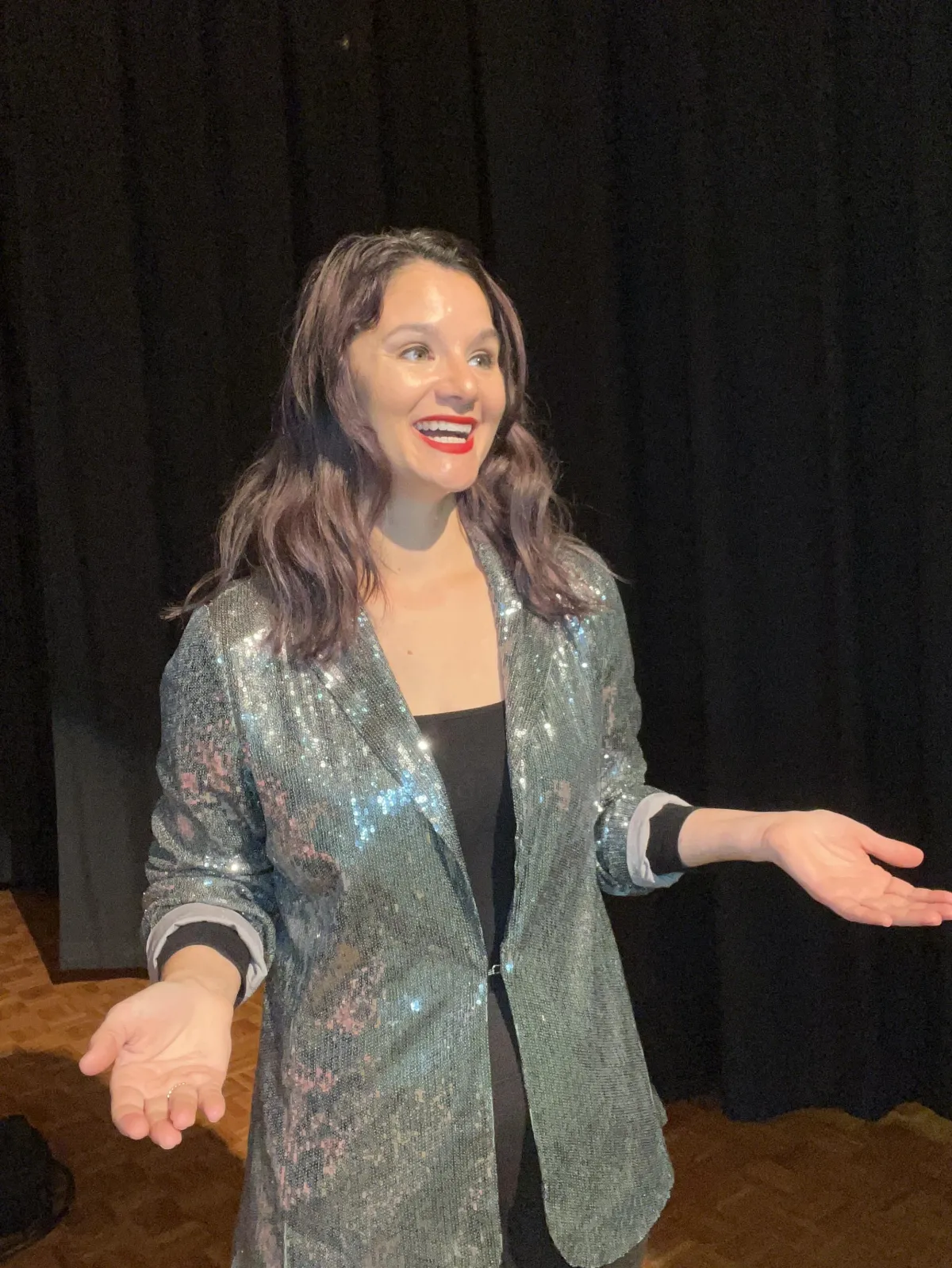 Kristina Proctor standing on a stage smiling with a sequins blazer