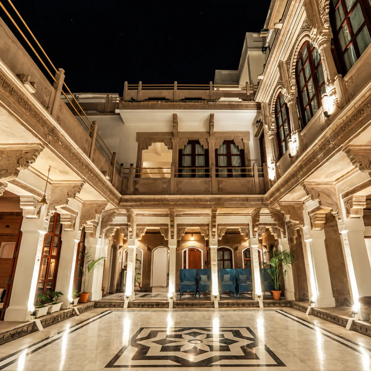 Luxurious, bright hotel interior featuring a large crystal chandelier, elegant seating, and ornate wall detailing