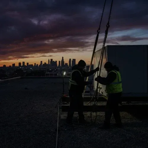 Commercial HVAC technicians installing a large rooftop package unit on a commercial building.