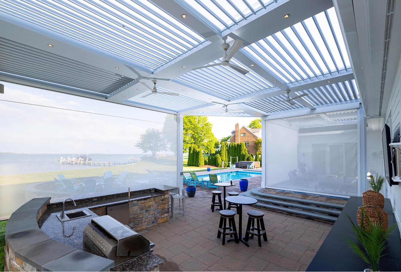 Covered outdoor living room with motorized louvered roof system for shade, ventilation, and comfort