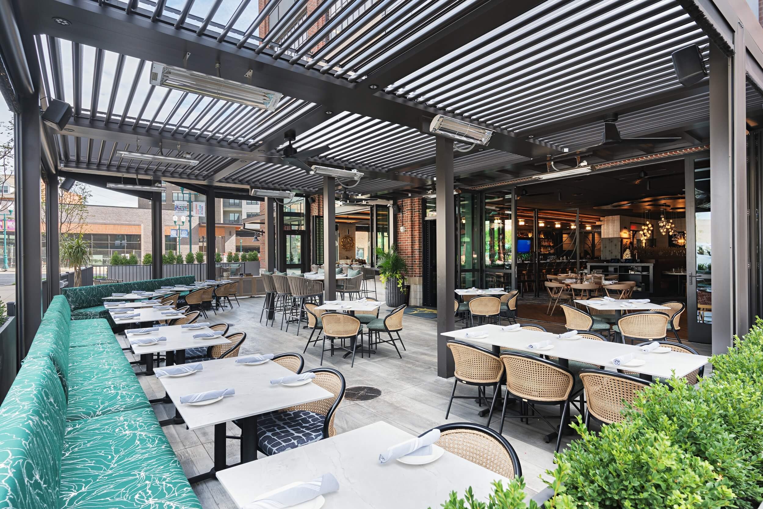 Modern outdoor restaurant patio with motorized louvered pergola providing shade and weather protection for dining area