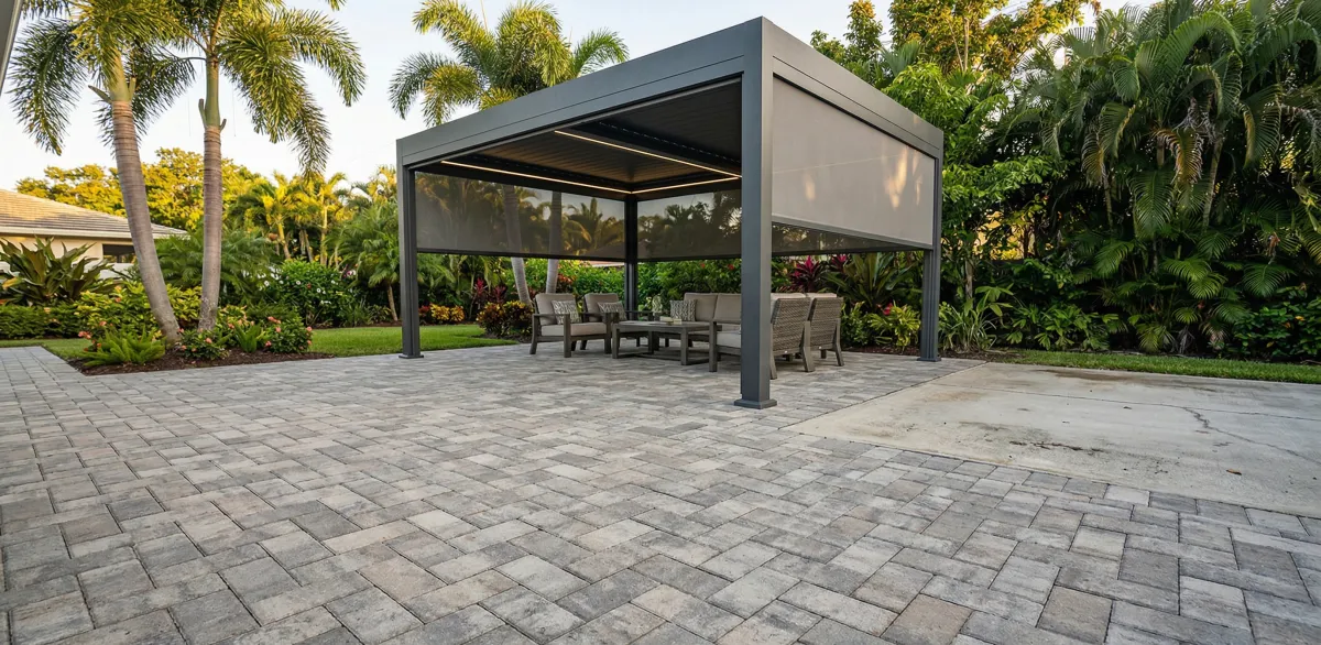 A newly installed paver patio with a modern aluminum pergola and retractable motorized screens in a Florida backyard. 