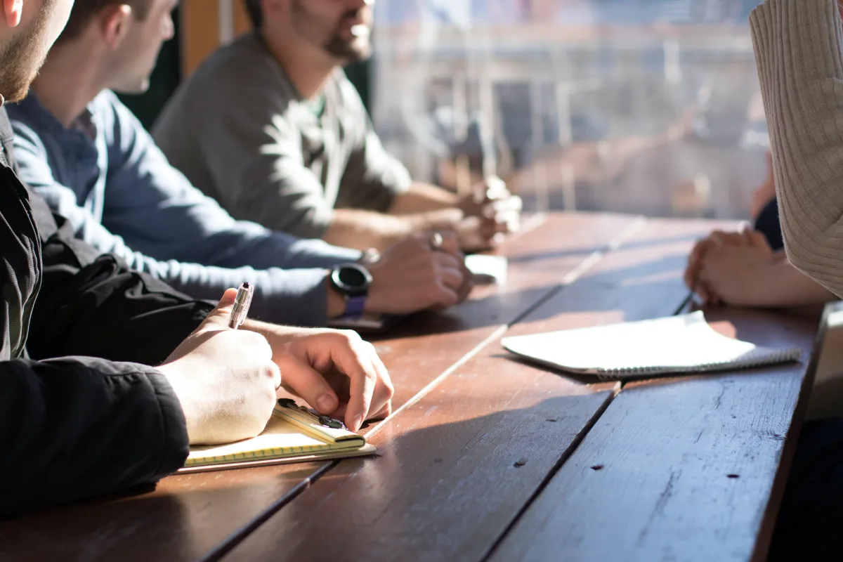 Group of people sitting at a table and taking notes