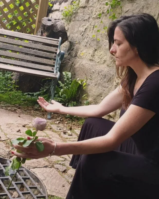 Woman engaging in sacred ritual, holding a rose in meditation, symbolizing deep feminine healing, spiritual awakening, and connection to nature.