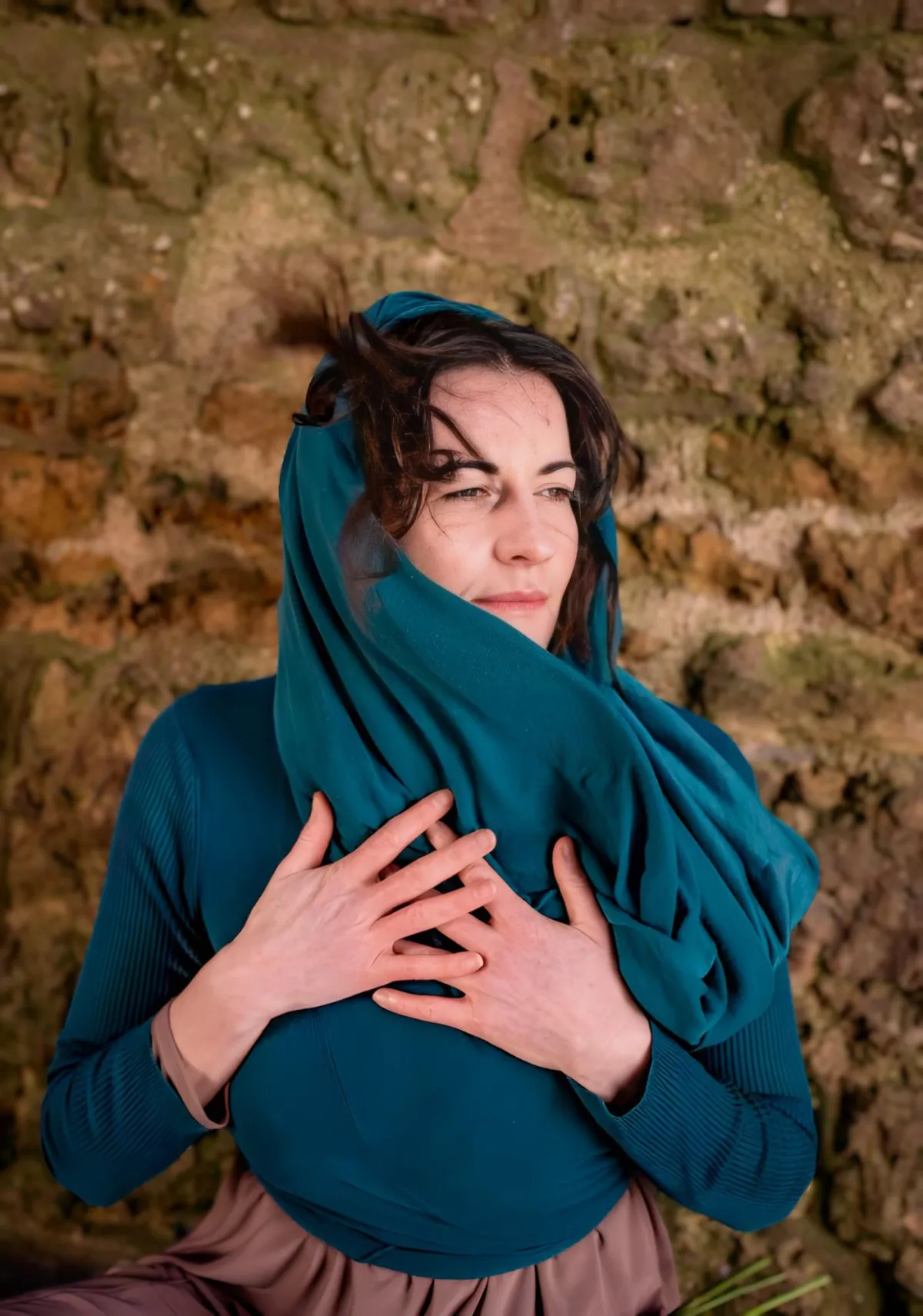 Woman with hands on heart, wrapped in teal shawl, embodying sacred feminine essence, yearning for deeper connection, healing, and divine love