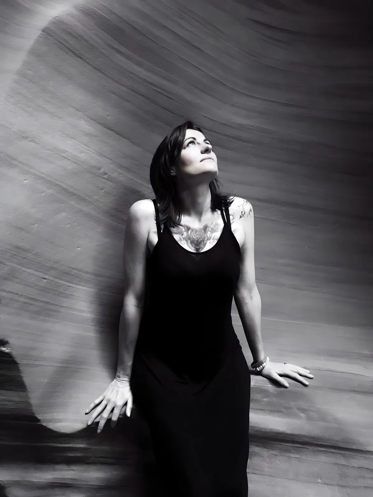 Woman in a black dress gazing upward, symbolizing spiritual awakening, inner strength, and the sacred feminine’s journey of self-discovery