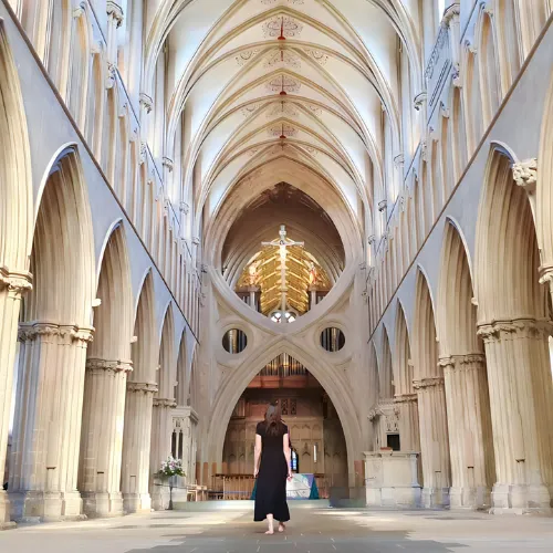 Woman walking barefoot in a grand cathedral, evoking themes of sacred feminine journey, spiritual awakening, and connecting with the divine.