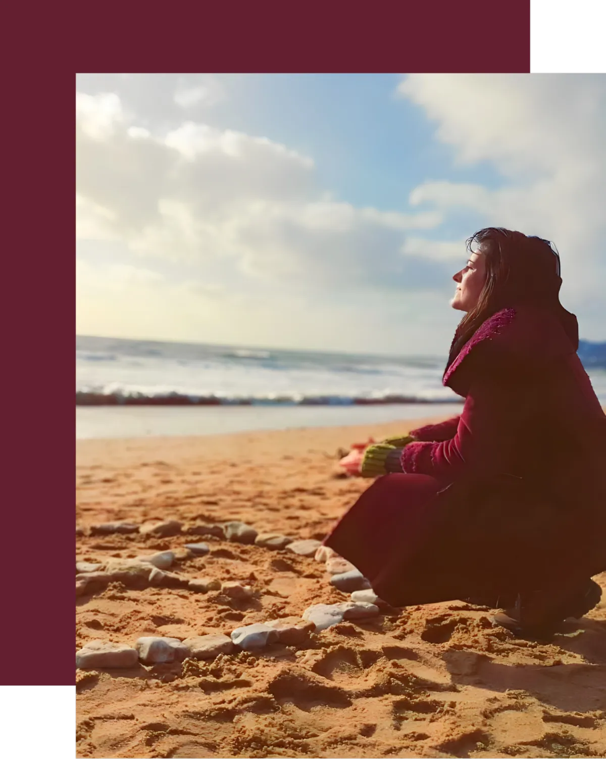 Woman kneeling on a sandy beach near a circle of stones, symbolizing grounding, sacred rituals, and connecting with nature and the divine feminine.