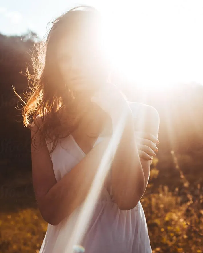 Sunlit woman embodying divine feminine energy, symbolizing spiritual awakening and the journey to reconnect with deeper feminine essence and self-love.