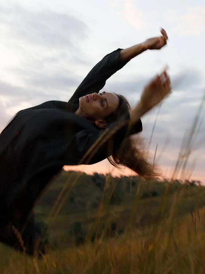 Woman dancing freely at sunset, embodying feminine liberation and spiritual awakening, reflecting the journey to reclaim personal power and authentic expression.