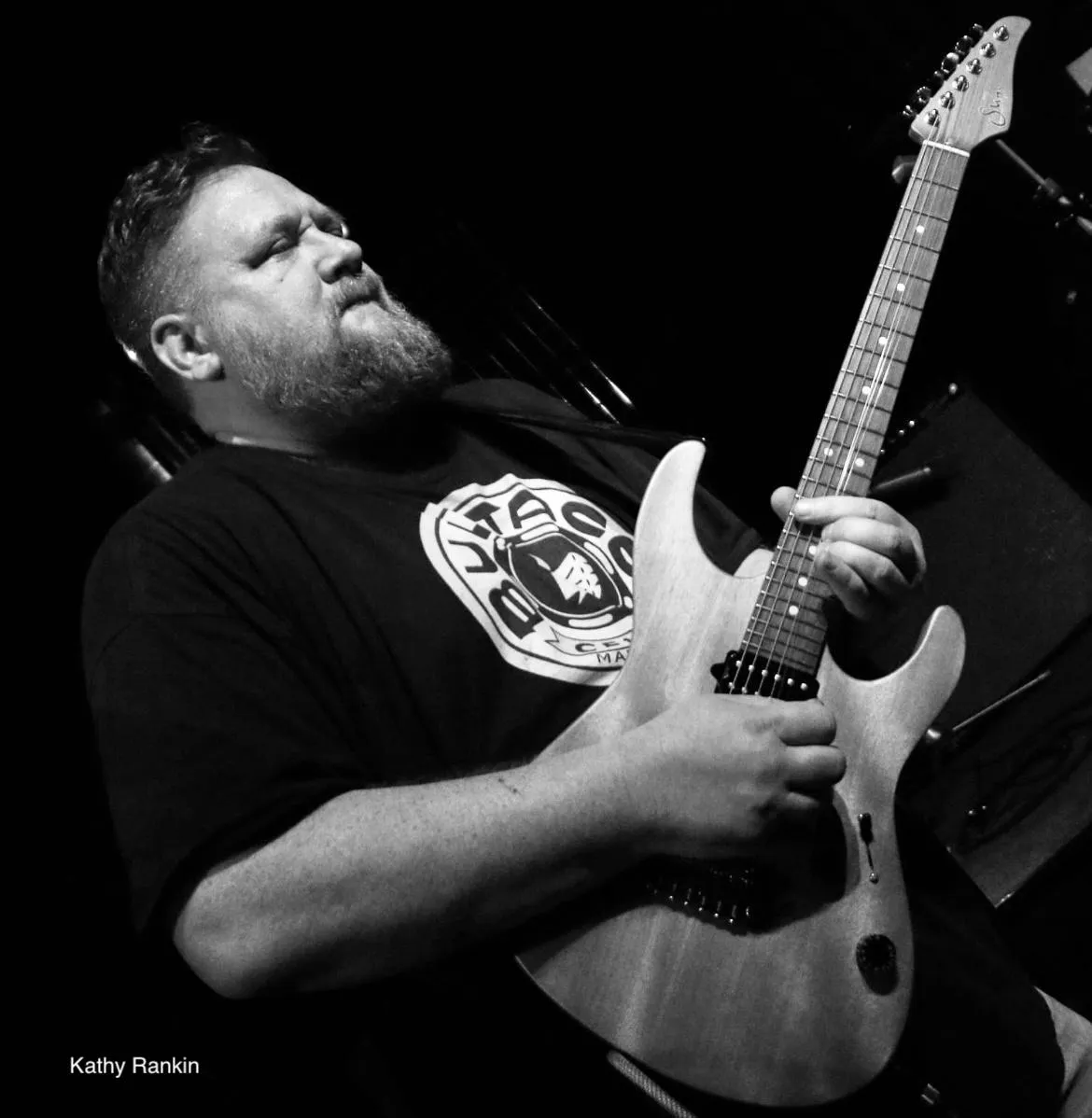 A contemporary portrait of two guitar instructors, one male and one female, from diverse backgrounds, standing in a bright rehearsal space. Both are holding guitars and smiling confidently, dressed in casual attire. The setting is modern and welcoming, with natural sunlight and a friendly atmosphere.