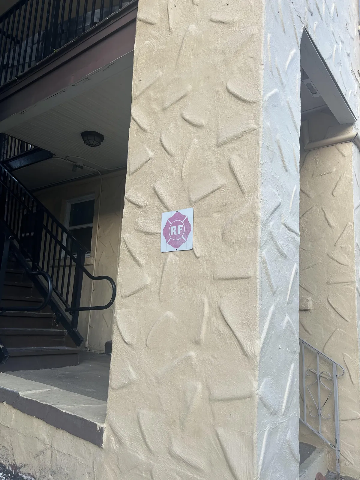 Stucco textures on a tan wall with a fire sign 