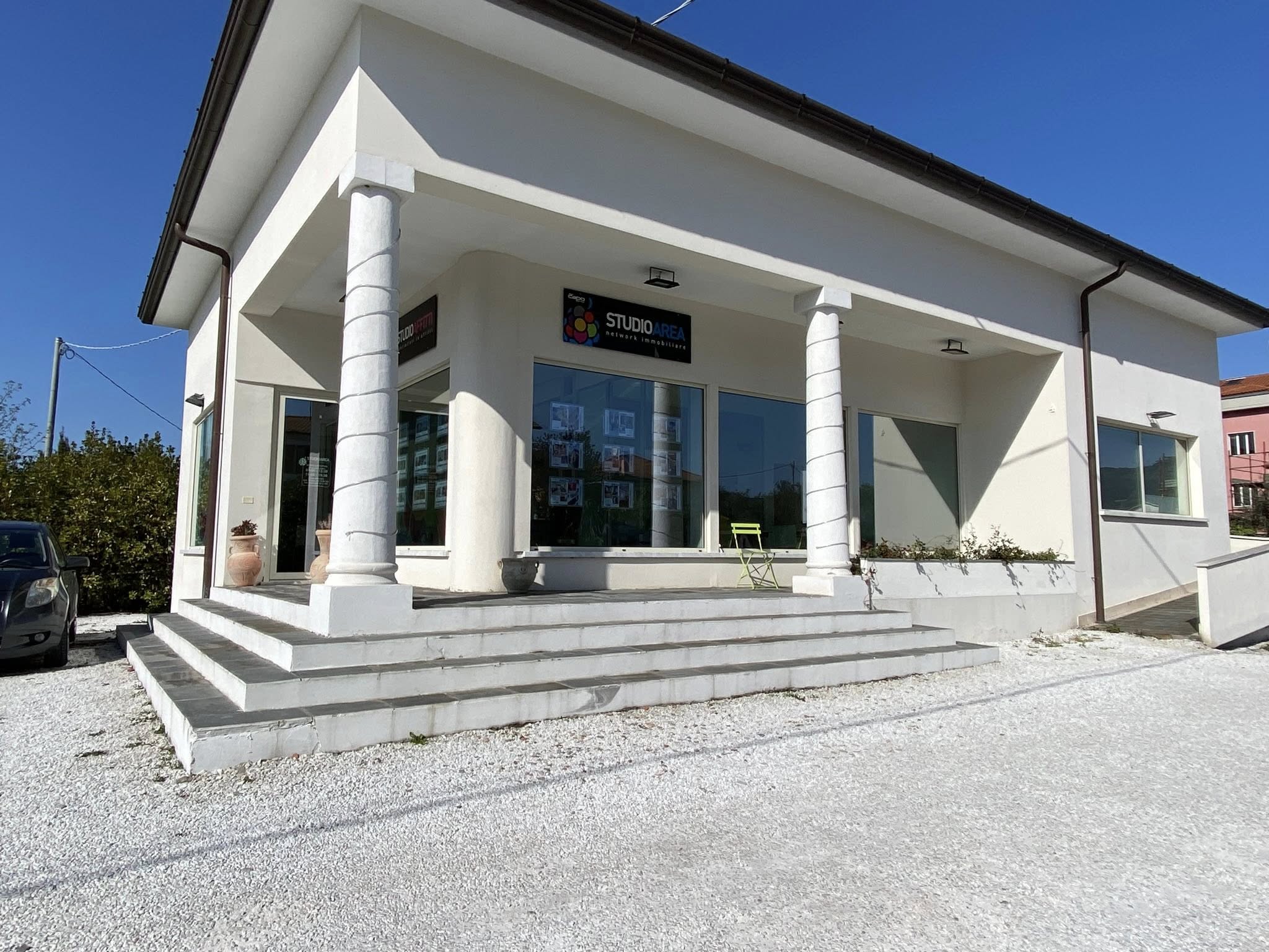 Famiglia felice in un soggiorno luminoso, madre, padre e due bambini sorridenti seduti su un divano moderno, ambiente arioso con grandi finestre, piante verdi e arredi eleganti, atmosfera accogliente e solare, stile fotografico contemporaneo, composizione naturale, luce diurna diffusa