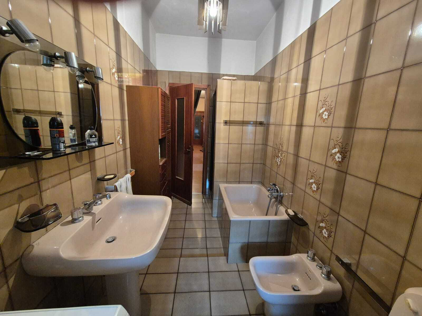 Expansive balcony lounge with plush seating, glass railing, and lush potted plants, overlooking the city at sunset. 3:2 aspect ratio.