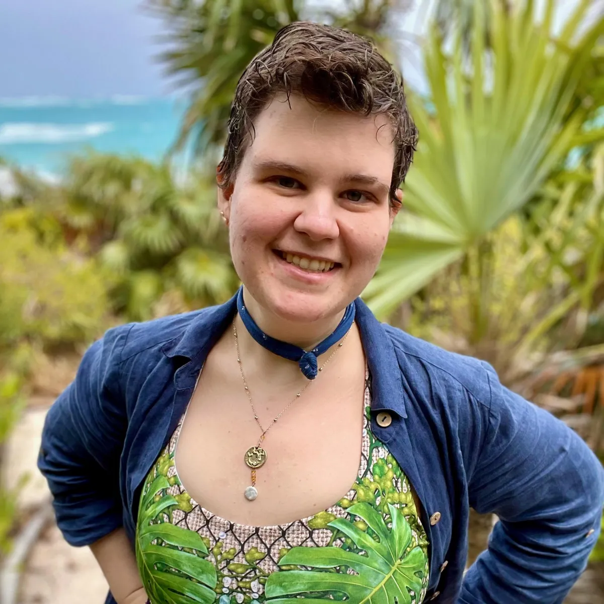 Justine the Mermaid Sewist, headshot with tropical beach behind them