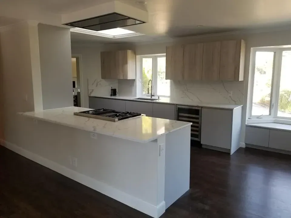 Modern kitchen remodel with black cabinets, quartz countertops, pendant lights, and marble backsplash