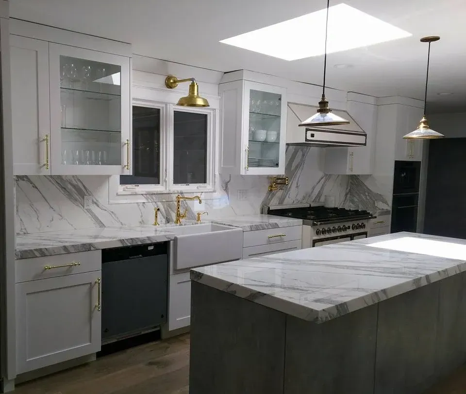 Bright kitchen remodel featuring white shaker cabinets, apron-front farmhouse sink, and marble countertops