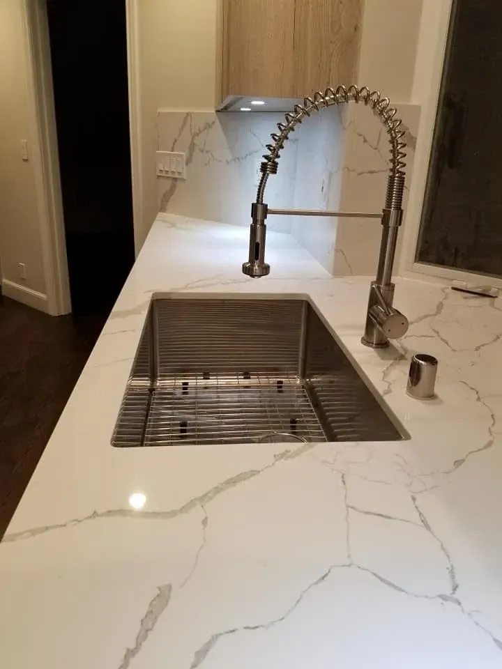 Bathroom renovation with dual vanity sinks, marble countertop, and modern wall-mounted lighting