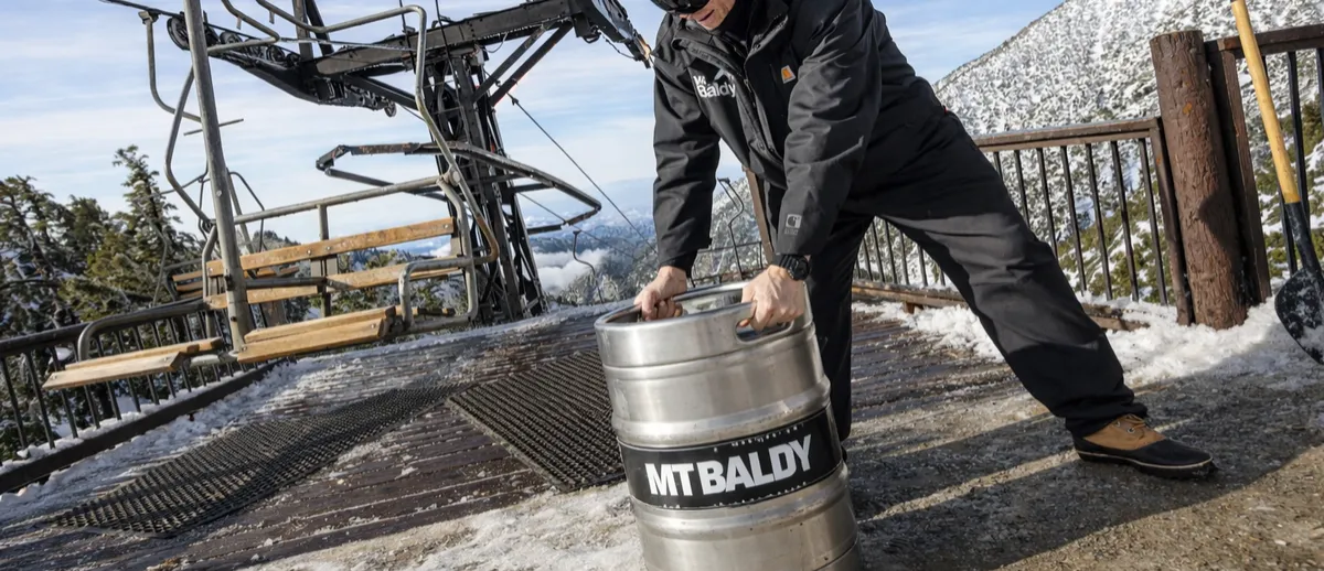 A brewer carrying a Mt Baldy keg past the chairlift