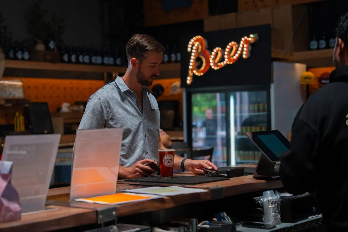 A bartender working behind the bar under the Beer neon sign