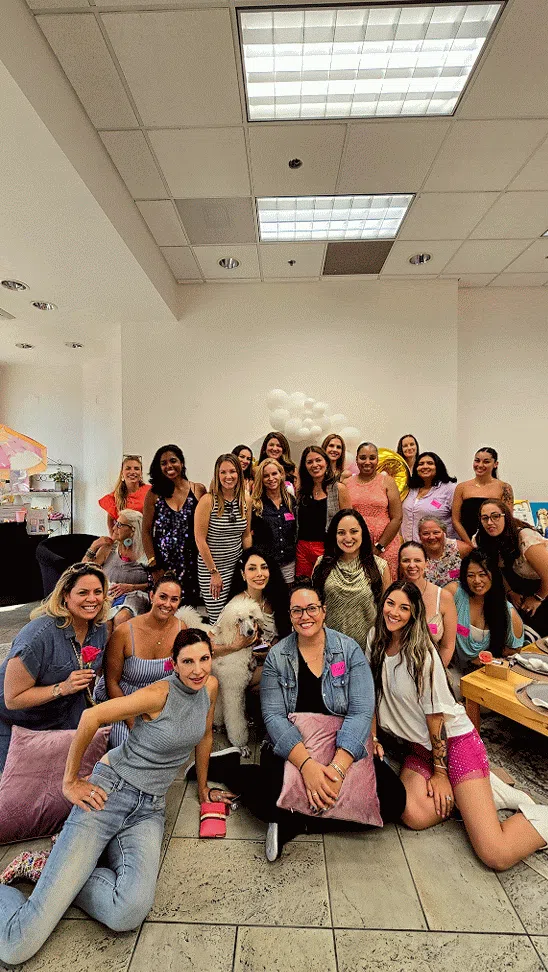 A group of women from The Foundress Table mastermind smiling and raising their hands at a live event — representing community, collaboration, and empowered female founders.