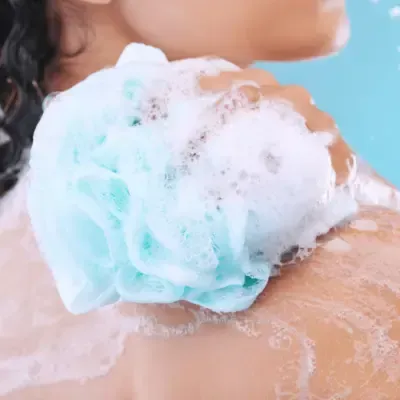 Woman scrubbing her body with a loofa and lathered soap