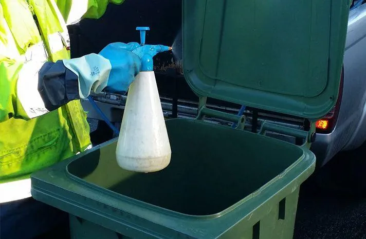 Eco-friendly sanitizer being applied inside commercial bin