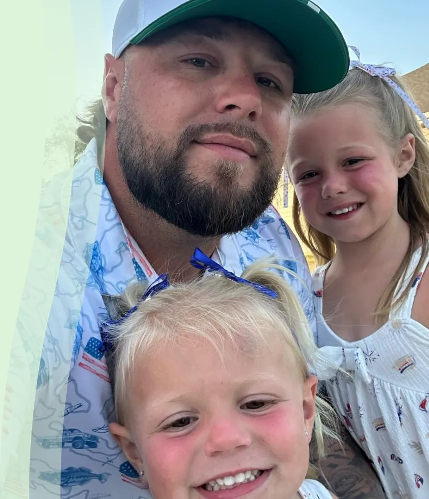 Owner of R&L Elite Bin Cleaning with his two daughters smiling outdoors