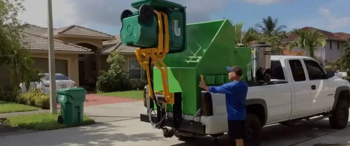 Truck lifting green trash bin for professional cleaning service