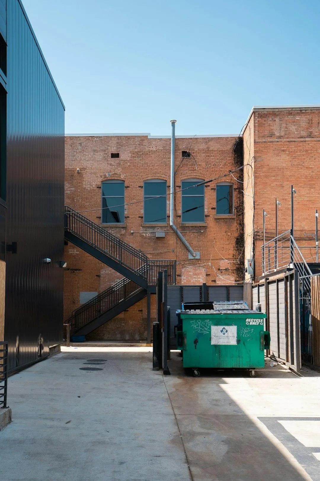 Worker pressure washing residential trash bin for deep cleaning