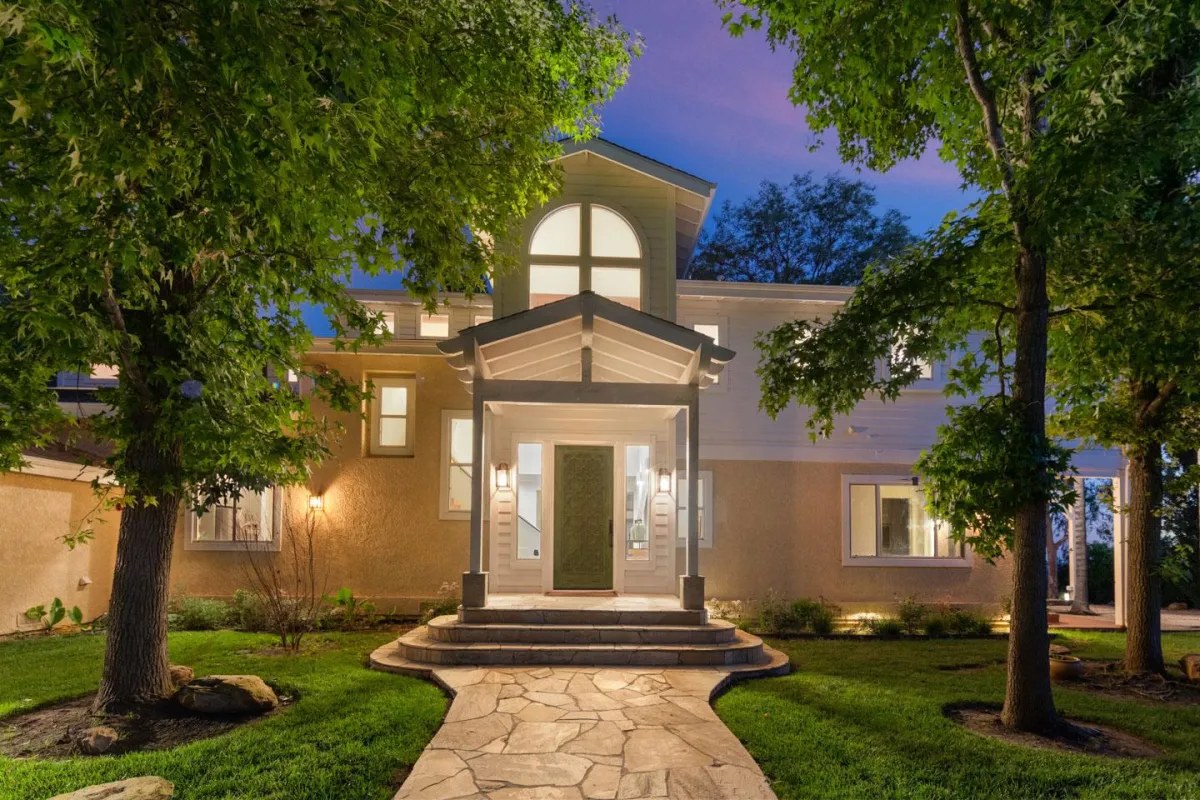 Two-story home exterior with mature trees and landscaped front yard