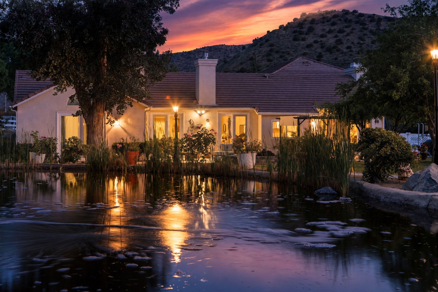 Illuminated home reflected in a landscaped pond at twilight