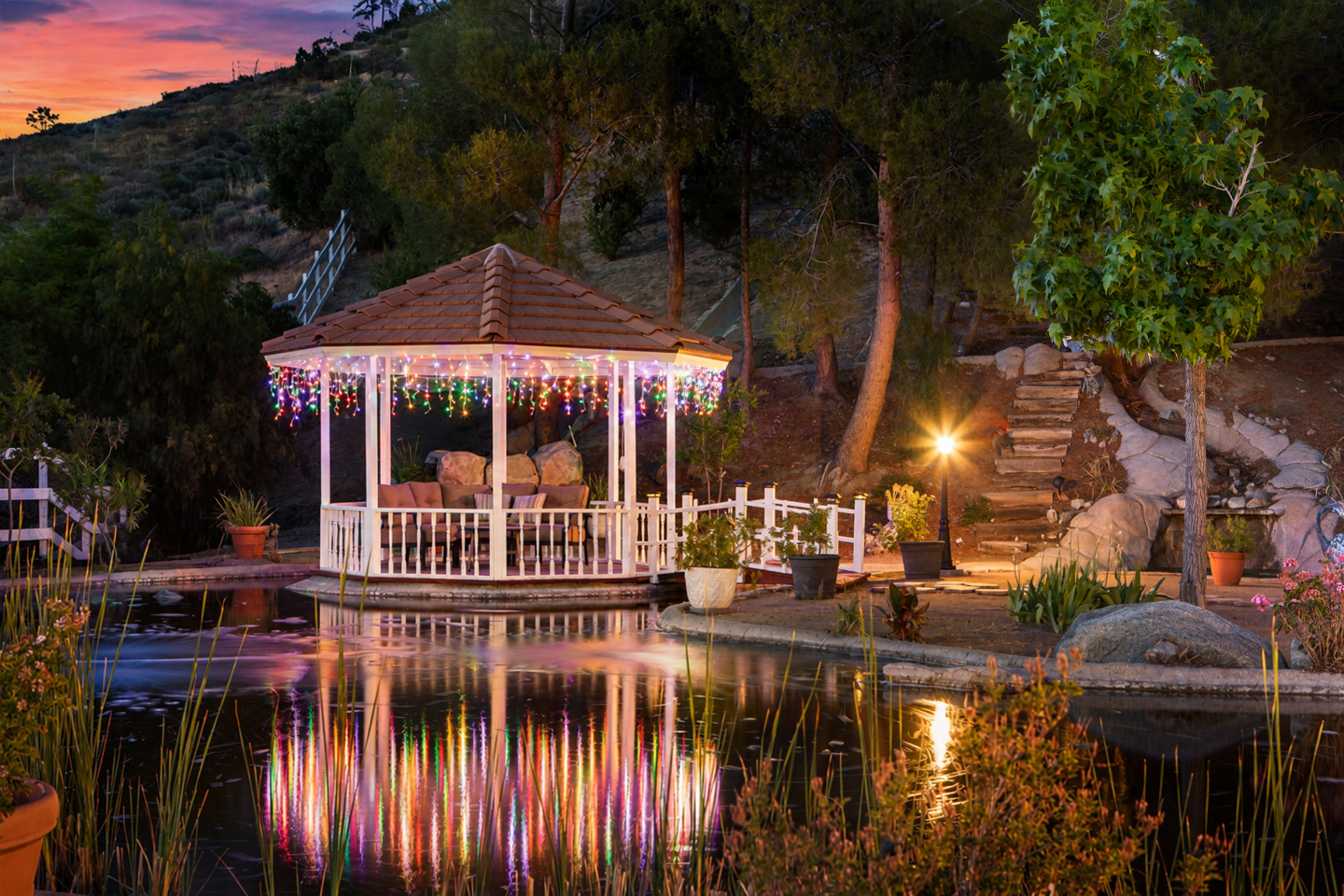 Outdoor pond and gazebo with landscape lighting at twilight