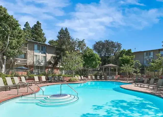 condo building with trees and a pool in the courtyard