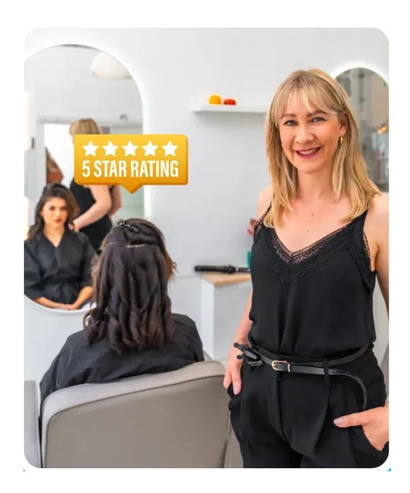 Smiling business owner in a salon with a five-star customer review rating displayed on screen.