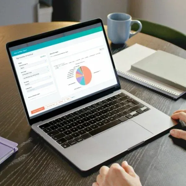 Hands typing on a laptop showing HubSpot analytics dashboard with data charts and lead performance metrics.
