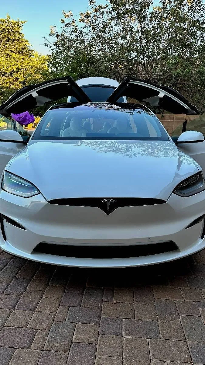 White Corvette with roof down and white Mercedes in the background