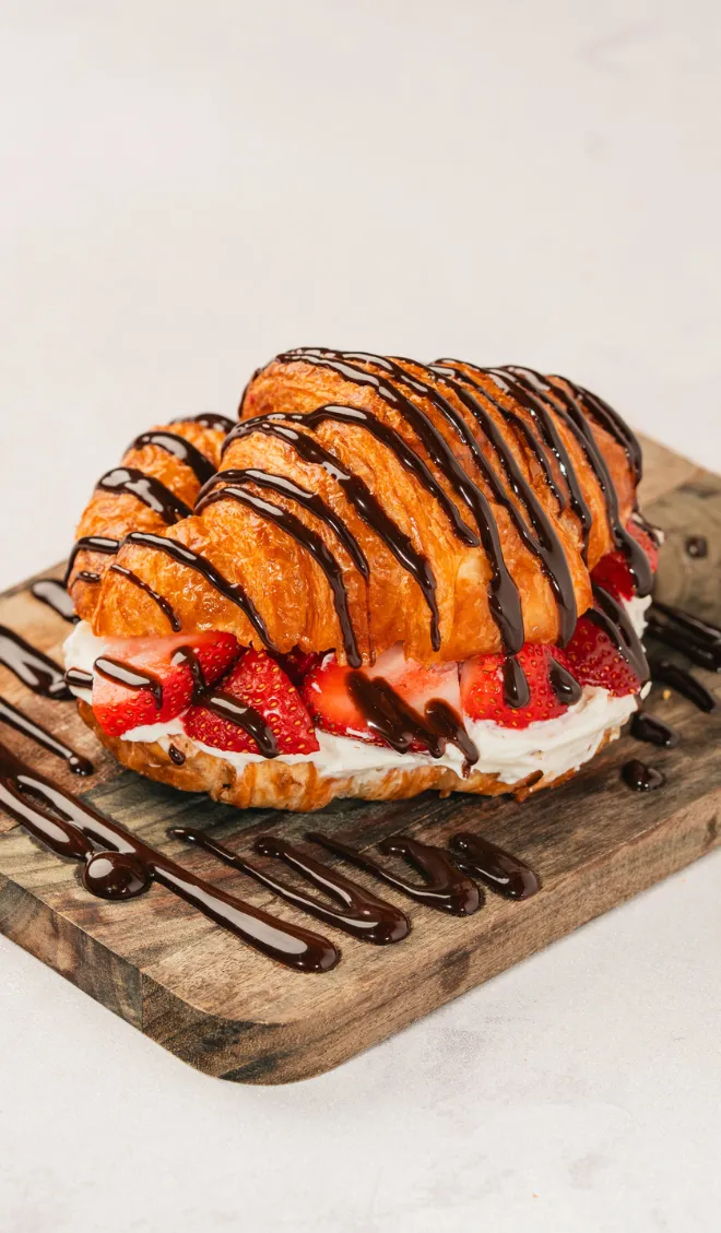Golden croissant with fresh strawberries, chocolate drizzle