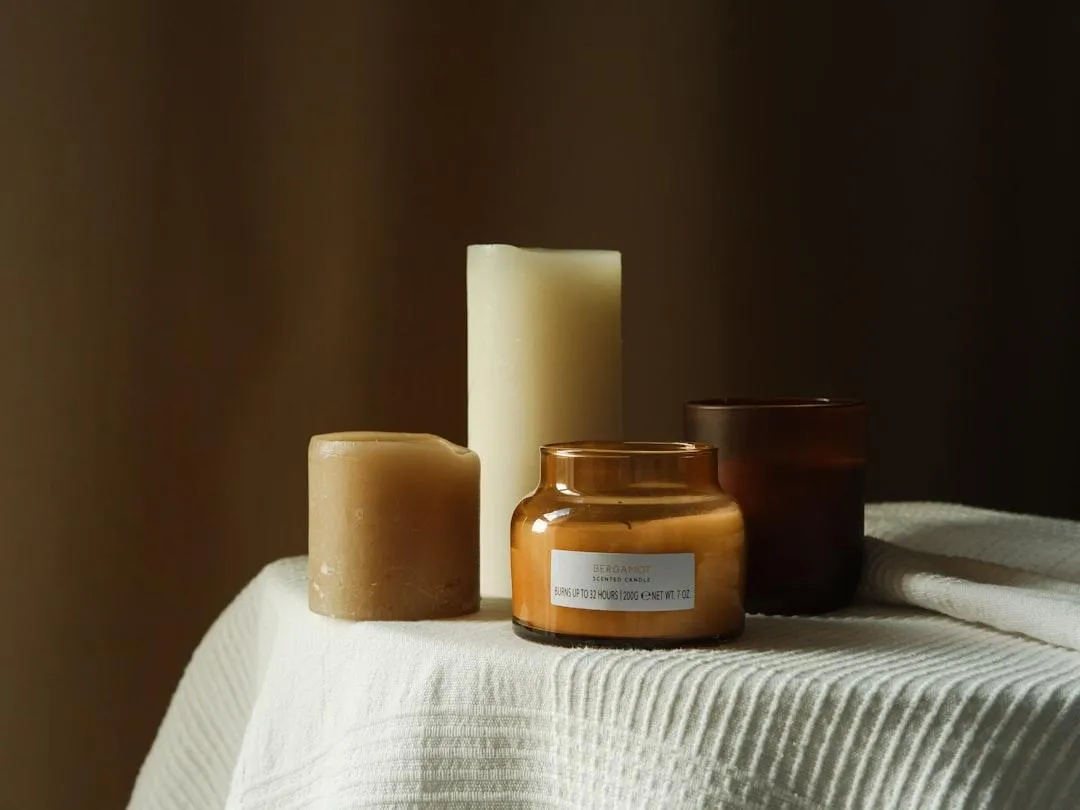Warm premium wellness still life with amber glass, candles and natural materials.