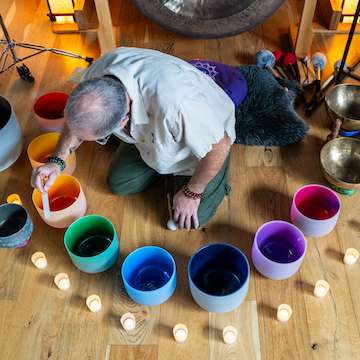 Kris seated in the center of a sacred sound circle with instruments.