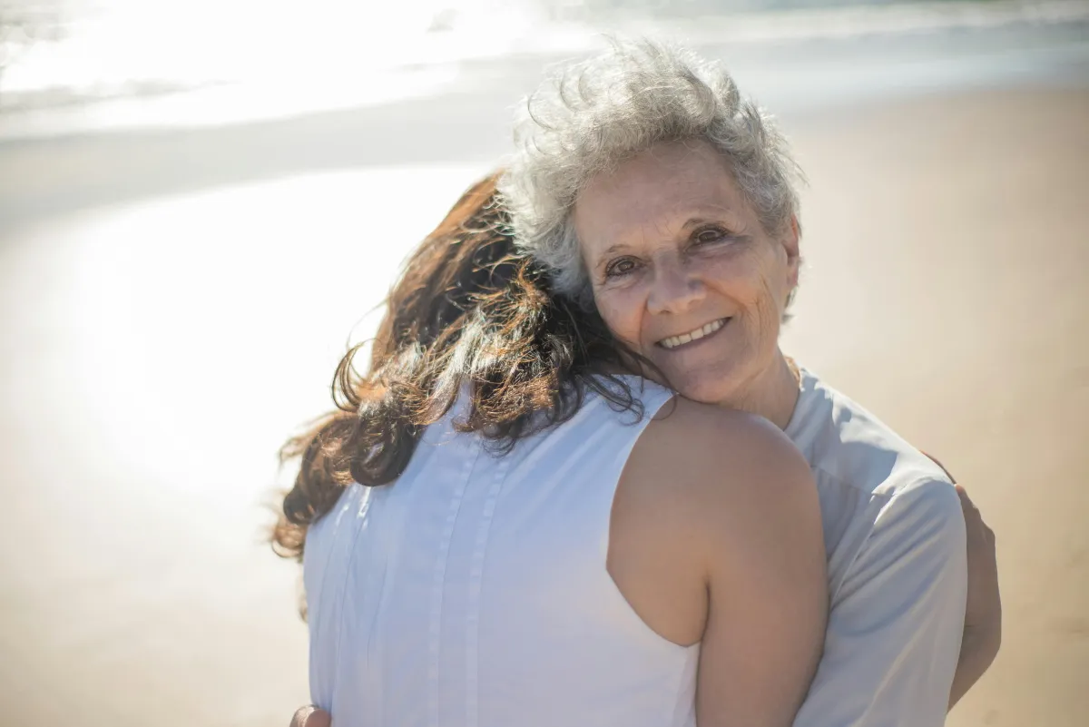Adult daughter hugging elderly mother while planning with final expense insurance