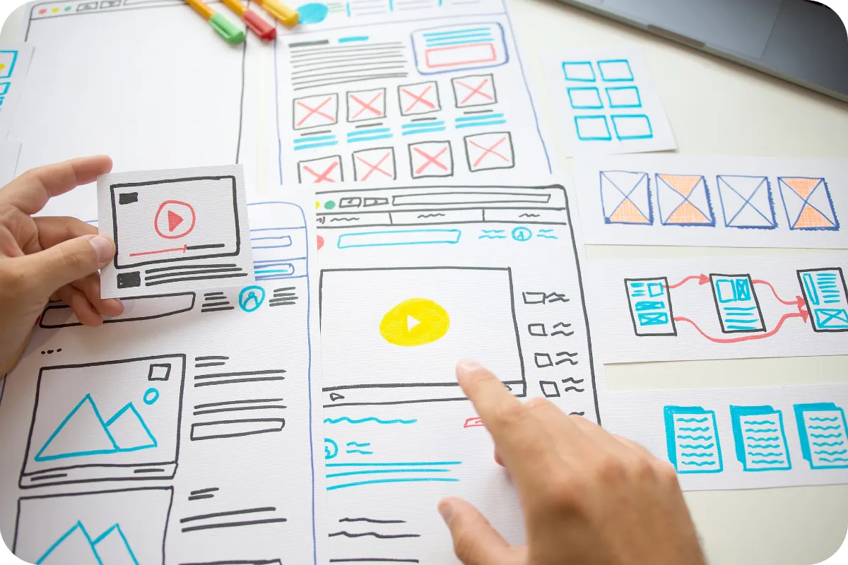 Hands working on a wireframe design layout for a business website, symbolising tailored digital solutions and user-focused design.
