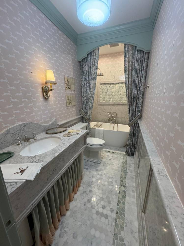 Elegant bathroom with marble vanity, mosaic floor tile and traditional chandelier