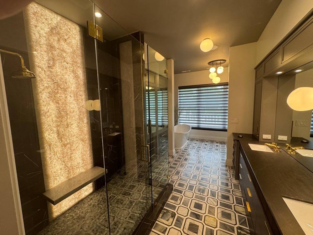 Luxury bathroom with geometric patterned floor tile, glass shower and dark marble accents